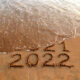 New year 2022 and old year 2021 on sandy beach with waves