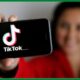 Woman showing a mobile Phone with TikTok Logo displayed on its screen