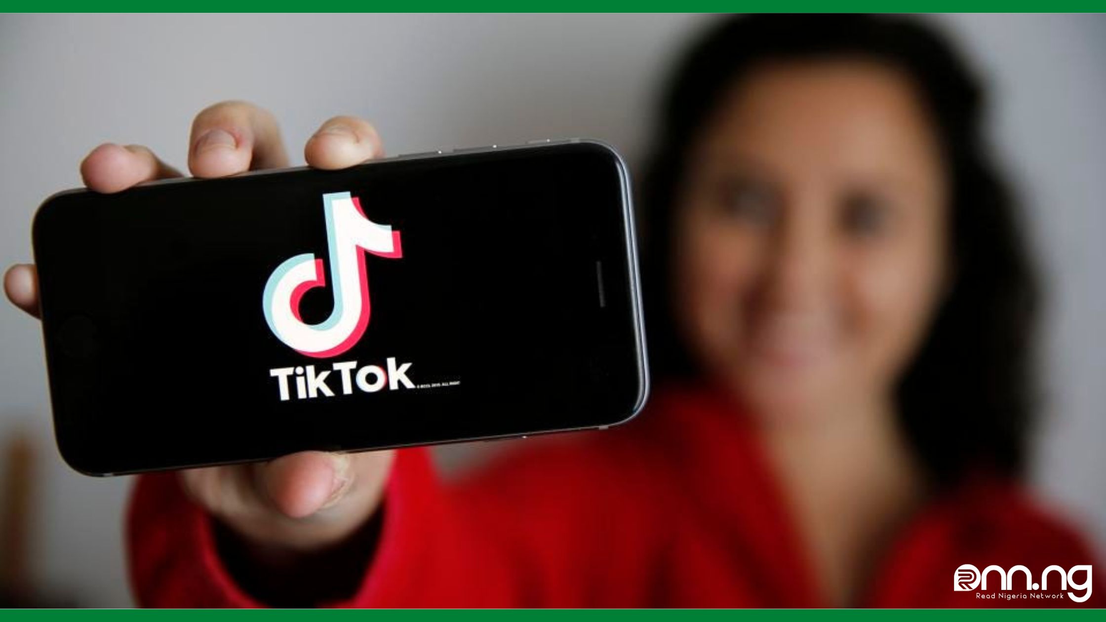 Woman showing a mobile Phone with TikTok Logo displayed on its screen